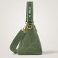 An olive green suede triangle shoulder bag with a matching green webbed strap featuring the white 'X PELLI' logo, displayed on a clean light gray background.
